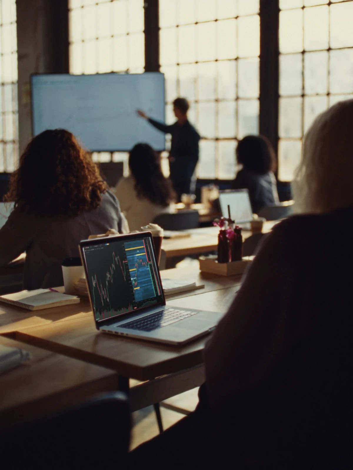 Une classe de trading dans un loft baigné de soleil ; au premier plan, un ordinateur affiche un graphique.